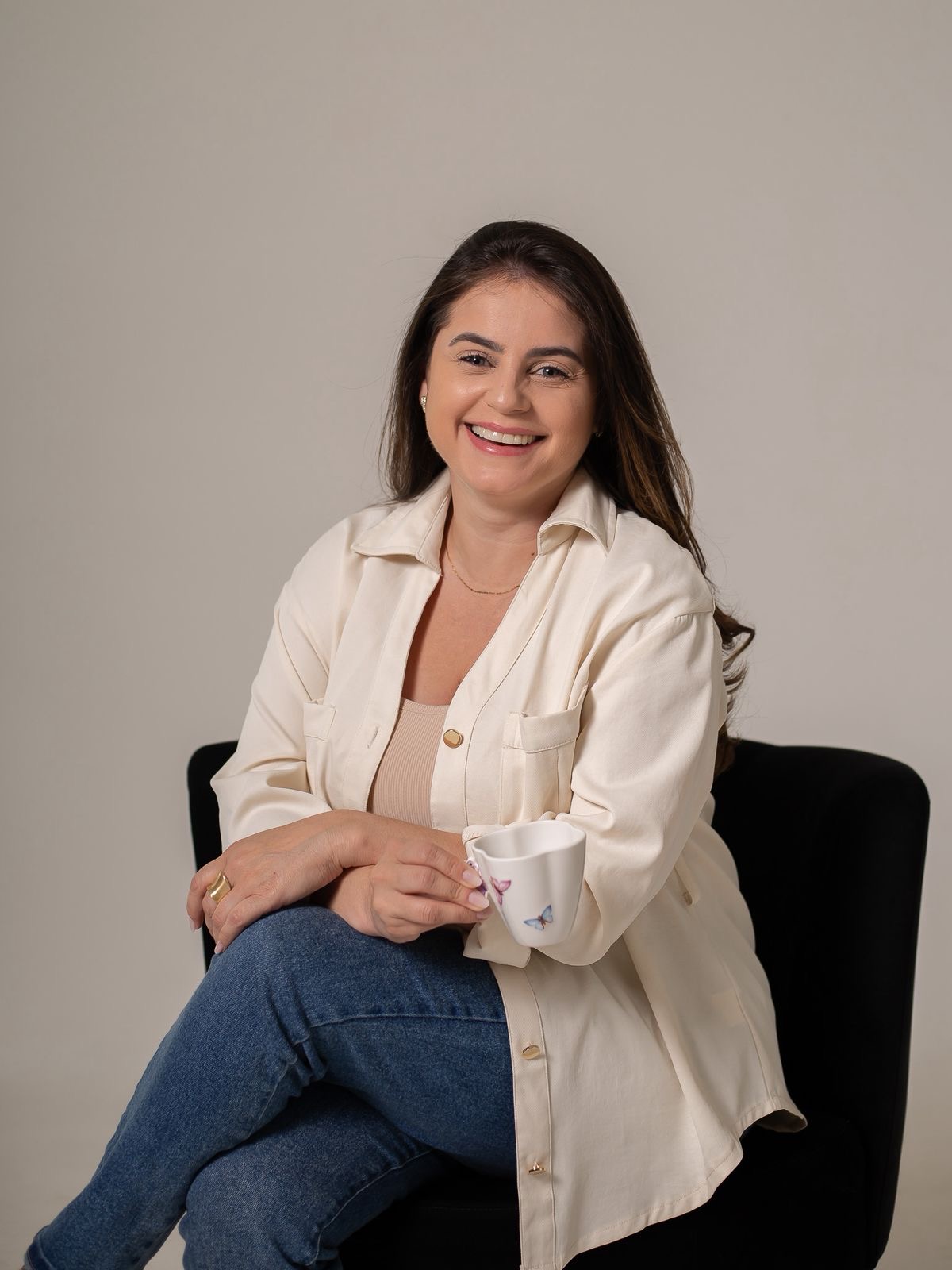 Francieli Zorzi sentada, sorrindo e segurando uma caneca